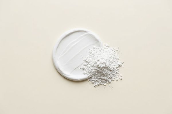 Weisse Zinkpaste mit Spatelspur neben Zinkoxid-Pulver