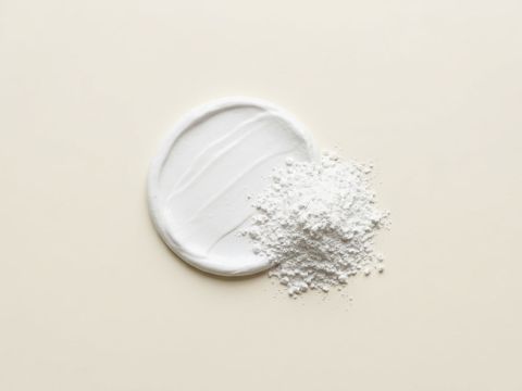 Weisse Zinkpaste mit Spatelspur neben Zinkoxid-Pulver